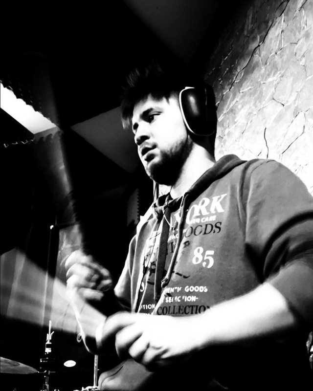 Jan Townley en la batería, con audífonos, en la sala de ensayo